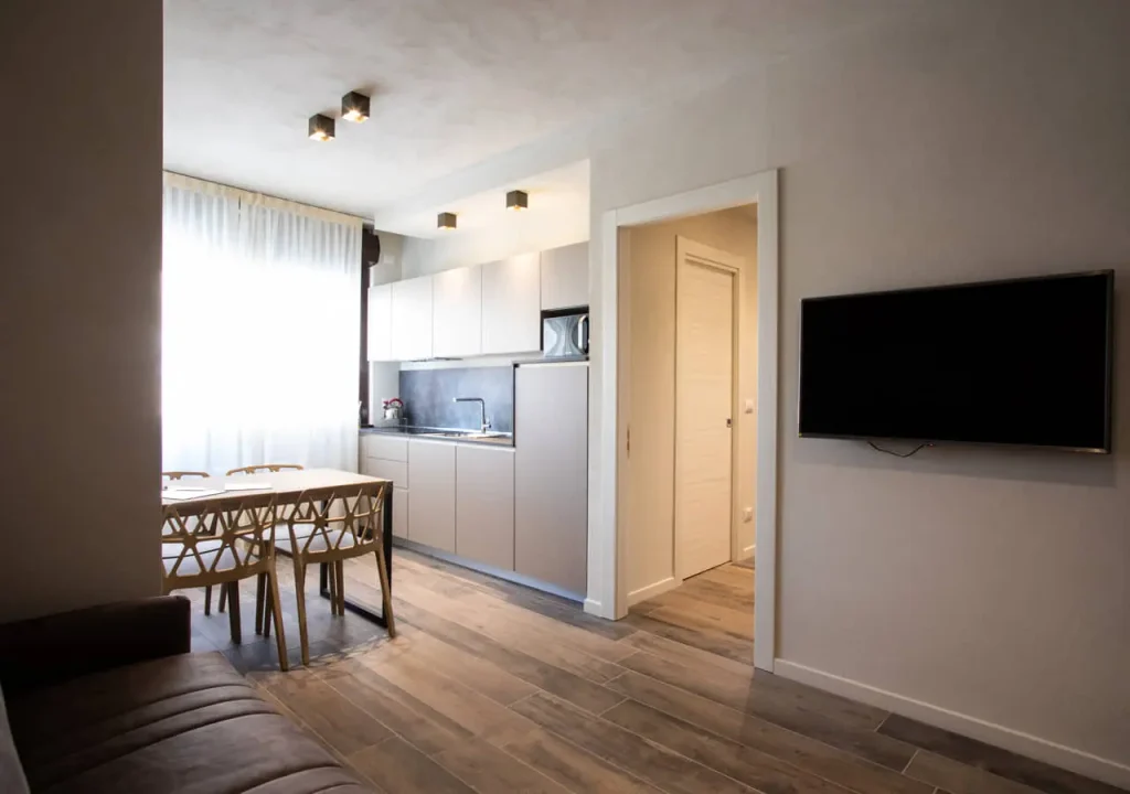 Cucina moderna con tavolo e soggiorno luminoso.